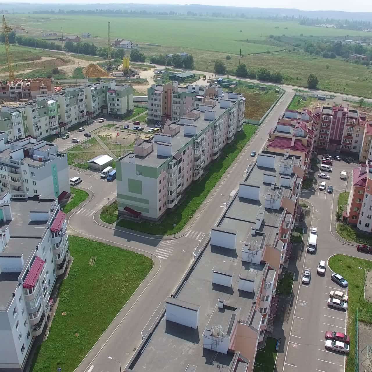 cars are passing along the road of the new district of the city on the background of high-rise buildings near the construction of modern buildings. Aerial view