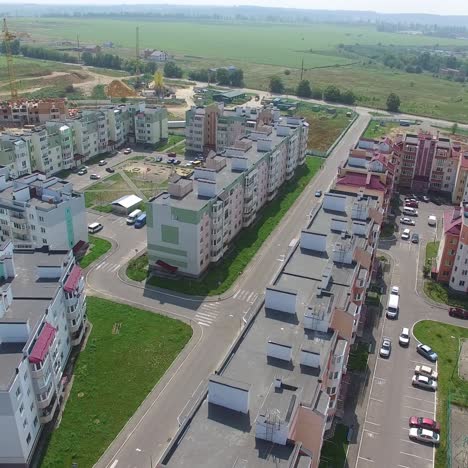 cars are passing along the road of the new district of the city on the background of high-rise buildings near the construction of modern buildings. aerial view