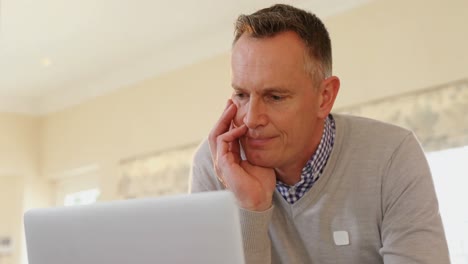 Mature-man-using-laptop-in-kitchen-4k