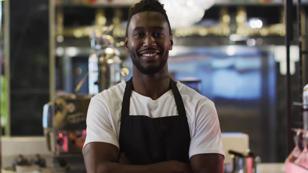 retrato de un barista afroamericano sonriendo a la cámara con un delantal en un café