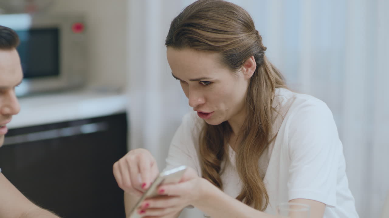 Closeup happy couple looking mobile phone at kitchen.