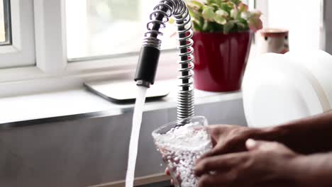 person filling glass by tap water