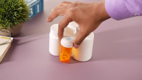 persona recogiendo pastillas de botellas de medicamentos en un escritorio