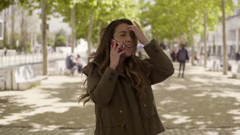 Smiling-young-girl-calling-to-friend-while-standing-on-sunny-street.