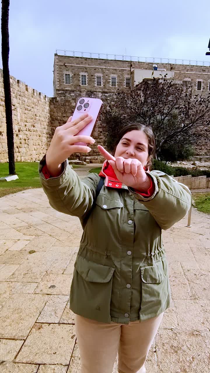 Young woman tourist taking selfies near the walls of Jerusalem old city in winter.