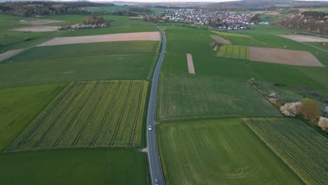 Curved-highway-with-several-cars-leading-through-green-meadows-in-rural-Germany