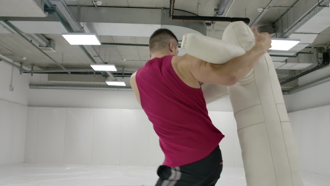A fighter works out a knee kick and a dummy throw in the gym in slow motion