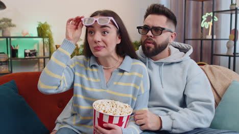 family man woman on couch eating popcorn, watching interesting tv serial, sport game online at home