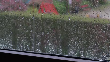 rain falling on window sill and dripping onto the surface with city in the background, still shot medium close-up