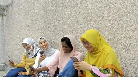 college girls in hijab using smartphone joyful mood