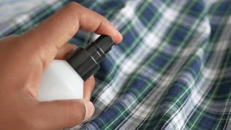 applying fabric spray to plaid shirt