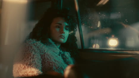 portrait of young melancholic woman sitting in car at night