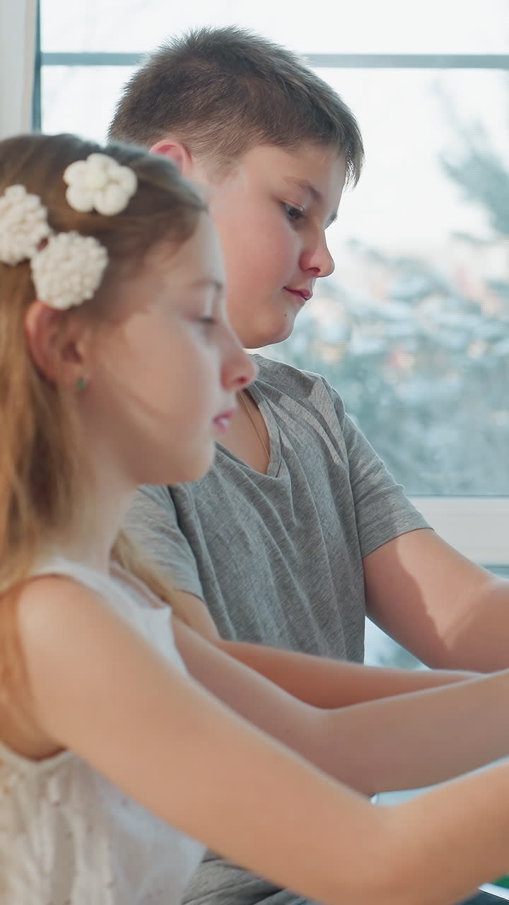 창가에서 피아노 듀엣을 연습하는 백인 남매, 은은한 햇살이 비치는 거실, 집중하는 표정, 서로를 지지하는 남매, 꽃 모양 머리핀을 꽂은 소녀, 건반 위의 손, 아늑한 홈스쿨링 음악