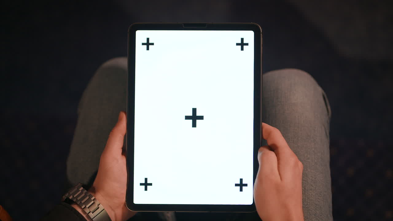 Hands of a man swiping on a tablet with white screen and tracking points, chroma key ready, close up shot