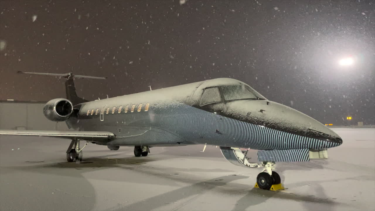 copos de nieve cayendo en un avión privado de lujo en la plataforma del aeropuerto de invierno