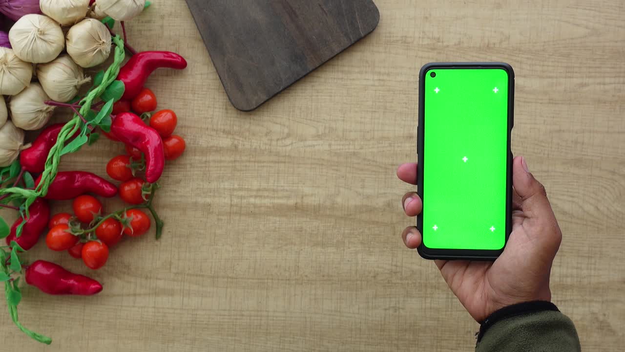 Smartphone with green screen on wooden table with food