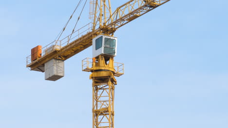 worker operates fixed jib tower crane on construction site in wind