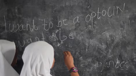 muslim islamic girl student writing occupations on the blackboard