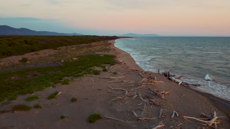 Epische-Filmische-Drohnenaufnahmen-Aus-Großer-Höhe-über-Einem-Sandigen-Sonnenuntergangsstrand-Am-Meer-In-Der-Nähe-Von-Alberese-Im-Legendären-Naturpark-Maremma-In-Der-Toskana,-Italien,-Mit-Wellen,-Inseln-Und-Einem-Dramatischen-Roten-Himmel