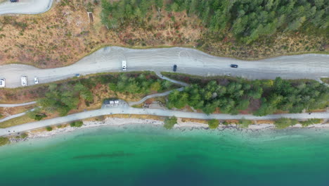 Schwarzes-Auto-Fährt-Auf-Der-Schotterstraße-Am-Ufer-Des-Achensees-Mit-Kristallklarem-Wasser,-Umgeben-Von-Montanem-Kiefernwald