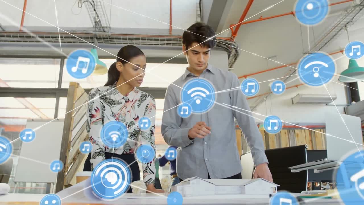 animación de una red de iconos digitales sobre un hombre y una mujer caucásicos discutiendo sobre un modelo en la oficina.