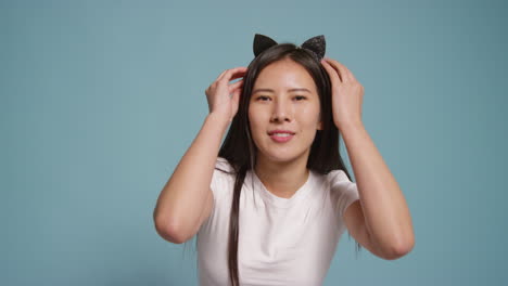 young woman in front of blue studio background dressing up and posing for photo booth style portraits