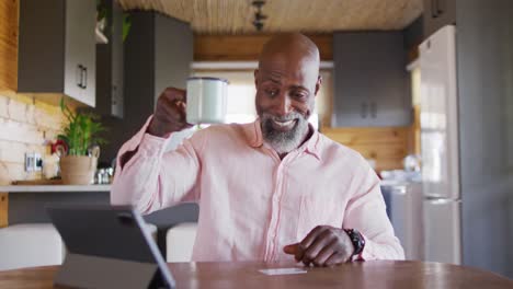 Feliz-Hombre-Afroamericano-Mayor-En-Cabaña-De-Madera,-Usando-Tableta-Para-Compras-En-Línea,-Cámara-Lenta