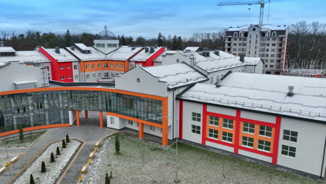 bright exterior of a new school building. modern architecture decisions in urban construction. trees and apartment blocks at the backdrop.