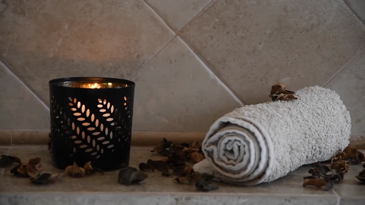 Latar belakang spa yang menenangkan, dengan lilin tersembunyi berkedip, beberapa kelopak kayu, dan handuk.