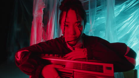 portrait of pretty asian woman with retro boombox in multicolored neon light