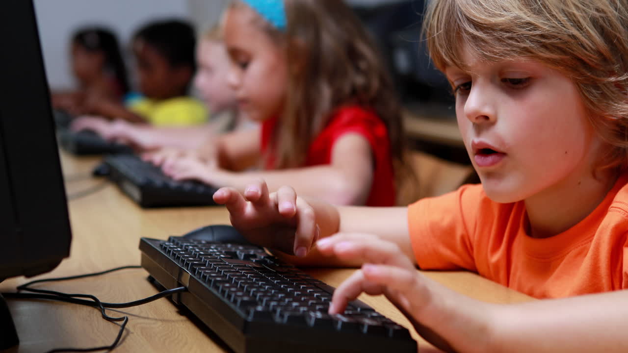 niño sonriendo a la cámara durante la clase de computadora