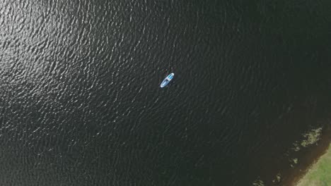 Descending-Rotating-Shot-Of-A-Young-Individual-Paddling-On-A-Small-Loch