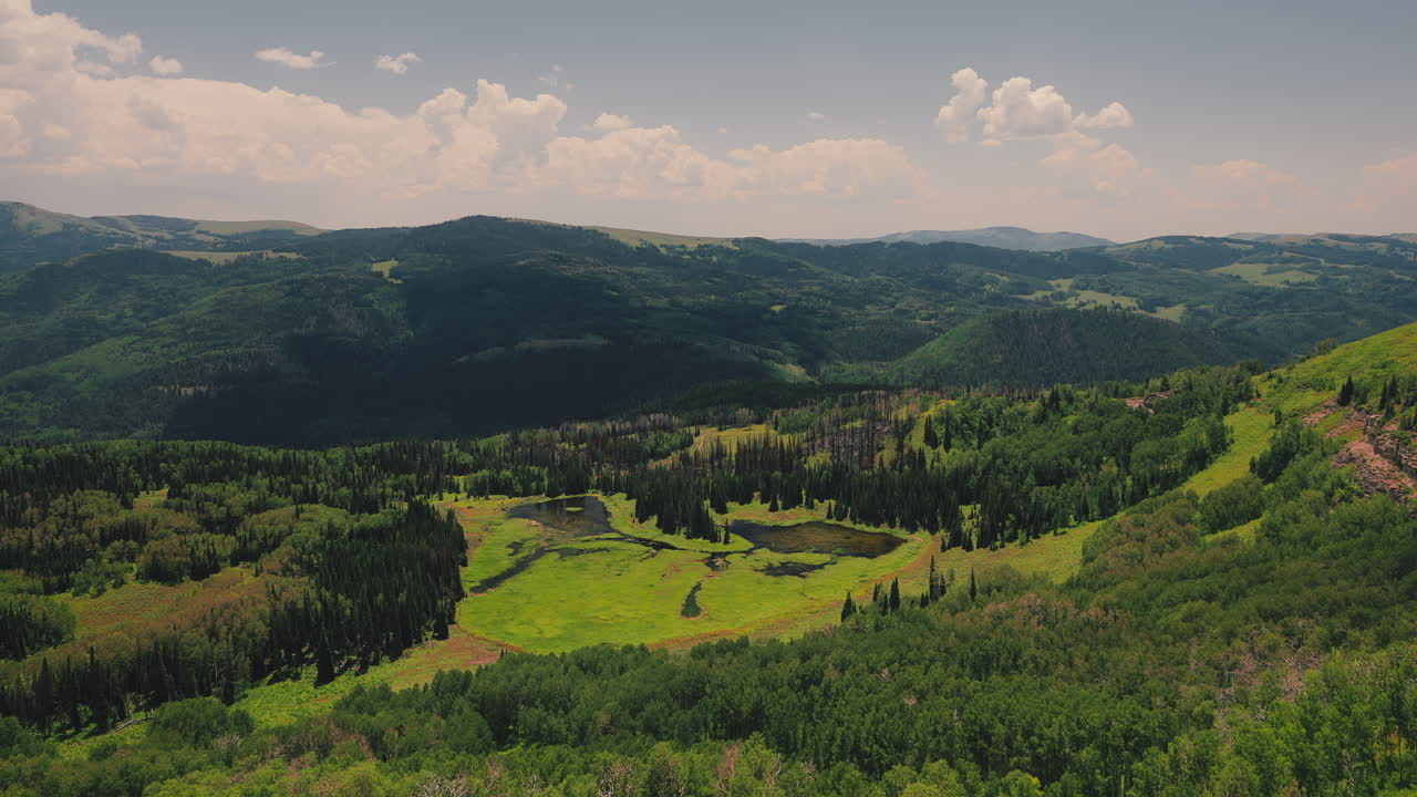 Cloud Shadows Over Forested Mountain Lake At Daytime. Time-lapse Pan-Left Shot