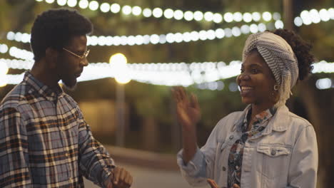 joyous african american man and woman chatting in park in evening