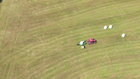 aerial top down of tractor with machinery cutting straw and producing straw bales on field