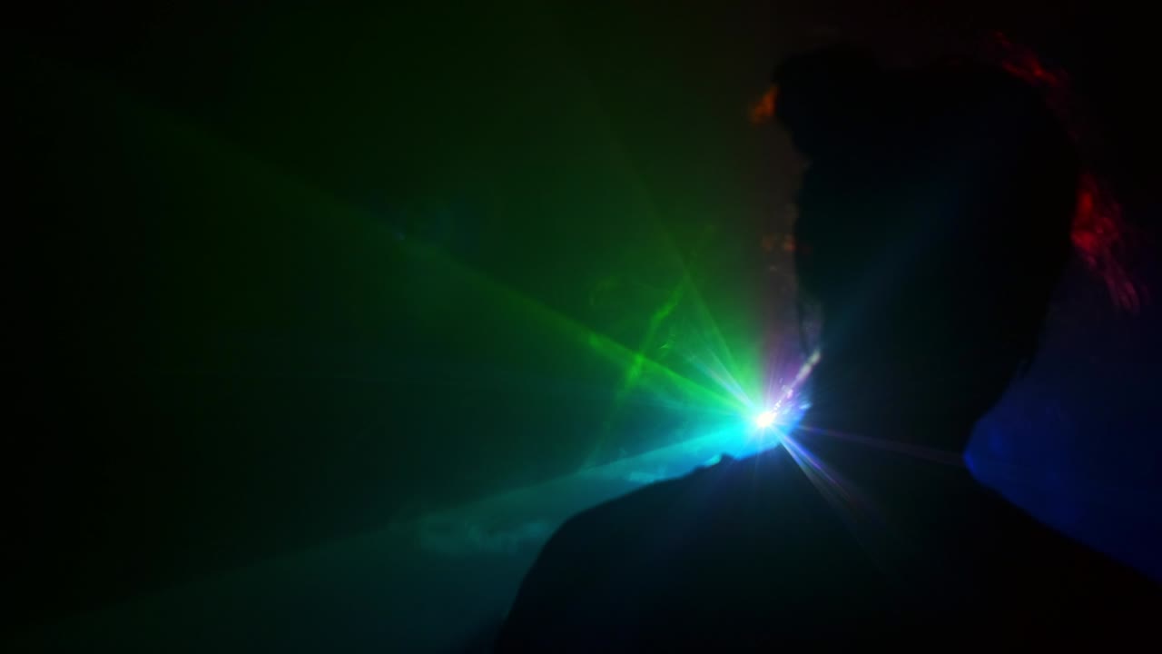 proyector. imagen de una niña joven en un fondo claro de diferentes colores moviéndose en la oscuridad. el humo llena el triángulo con la cabeza de la niña.