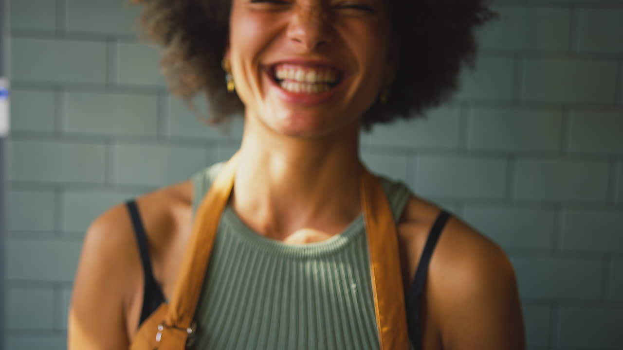 Ritratto di proprietaria o membro dello staff sorridente all'interno di un negozio o caffè, che tiene in mano una bevanda calda.