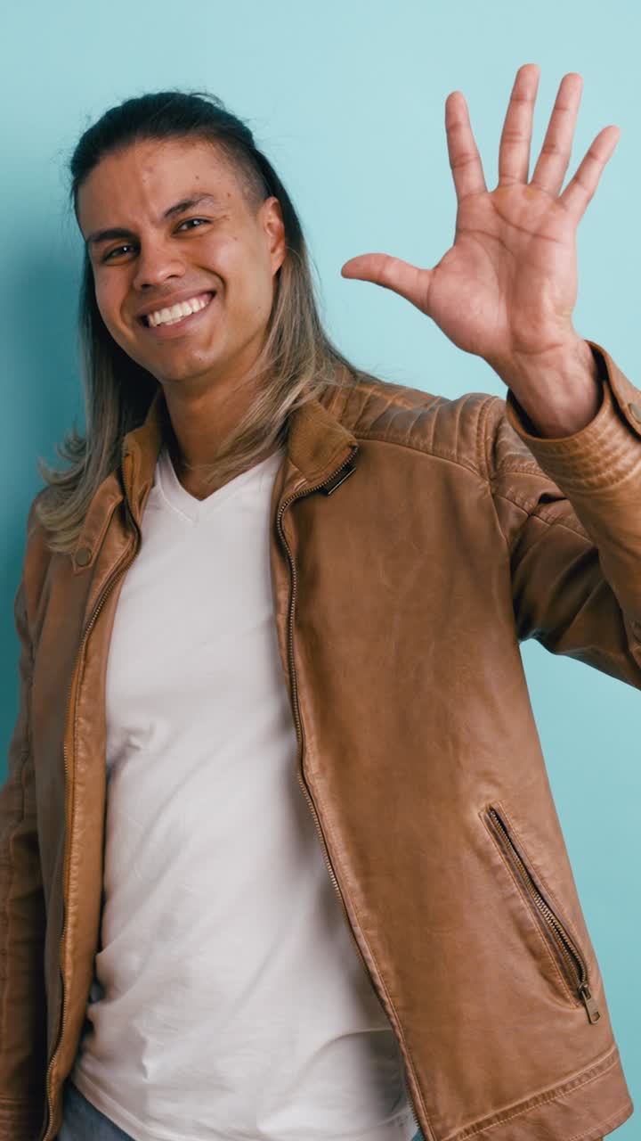 Giovane uomo felice che saluta e sorride in studio