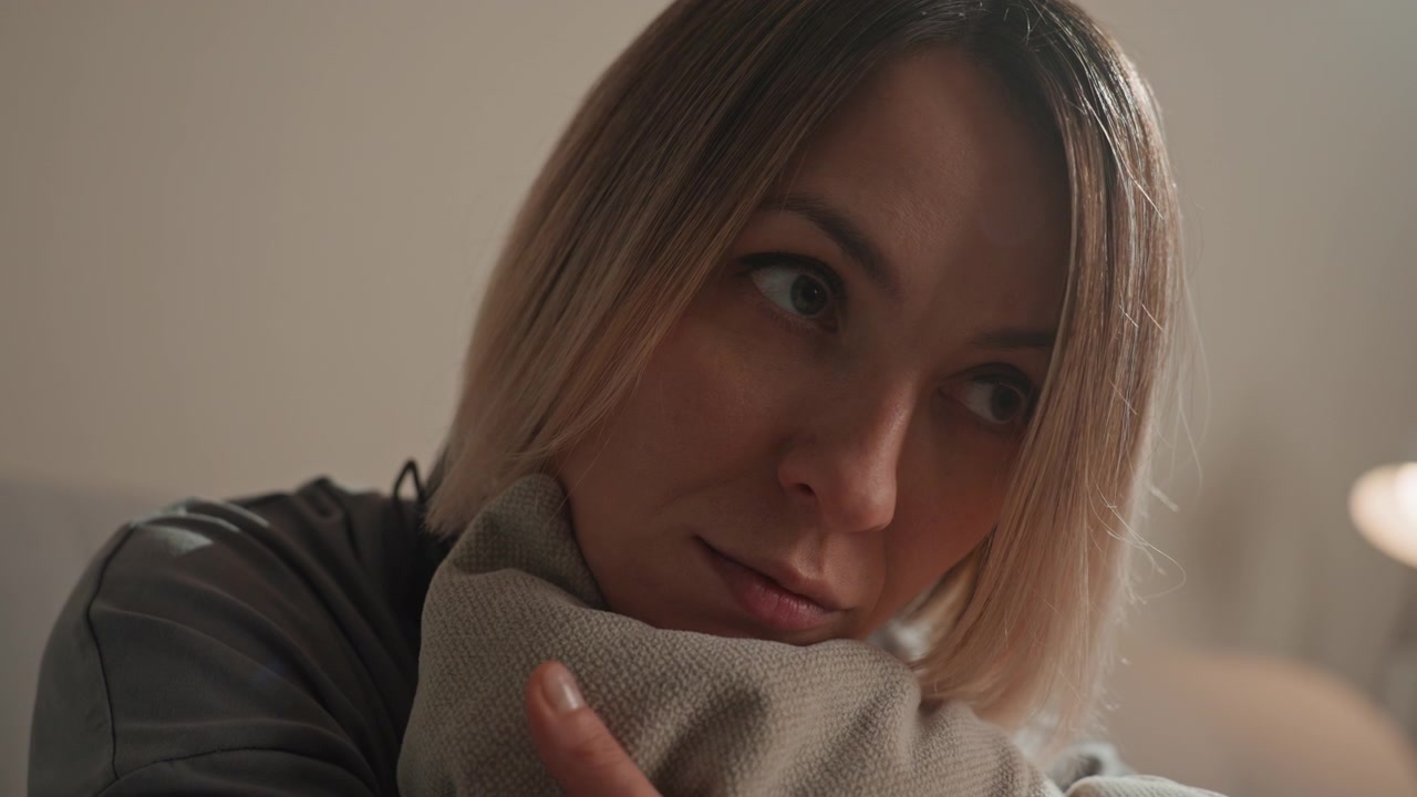 Mulher caucasiana com fones de ouvido abraçando um travesseiro, close-up íntimo em apartamento aconchegante, amante da música sonhando e buscando consolo, luz quente da lâmpada e bokeh suave, olhar esperançoso e cinematográfico calmo