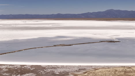 Aerial-view-of-National-Route-52-crossing-the-natural-salt-flat-of-Salinas-Grandes-in-Jujuy,-Argentina