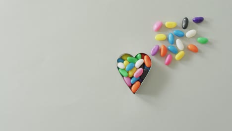 video of multicoloured jelly sweets in heart shaped container with copy space on white background