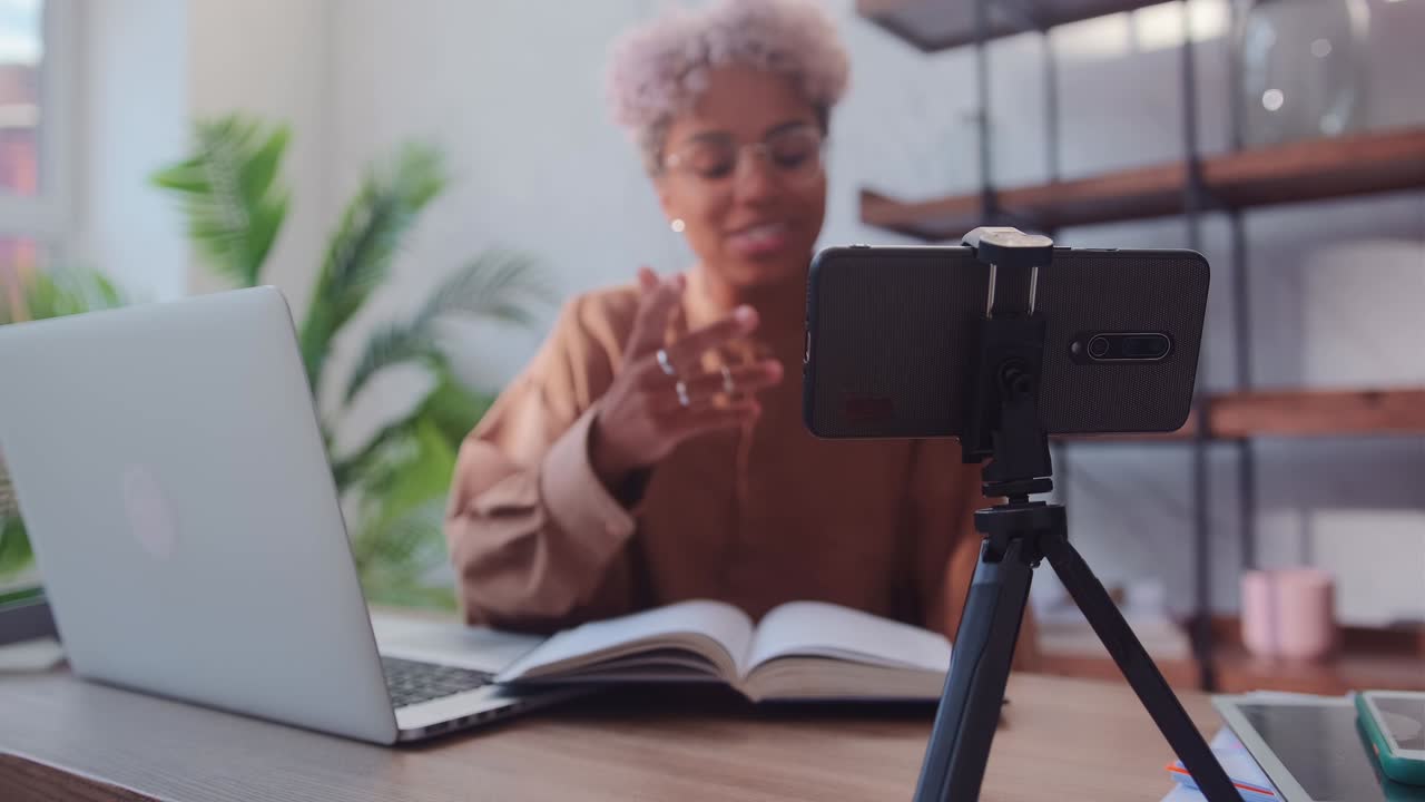Young cheerful african american woman blogger leads video podcast in phone