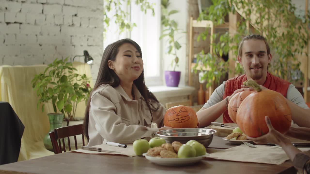 친구들은 테이블에 앉아서 할로윈 호박에 대해 이야기하고 있습니다.