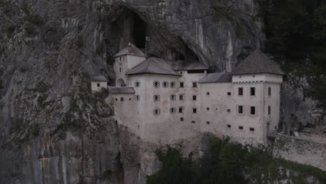 drone video of a crane plane descending over the rredjama castle in slovenia with people coming out of the interior