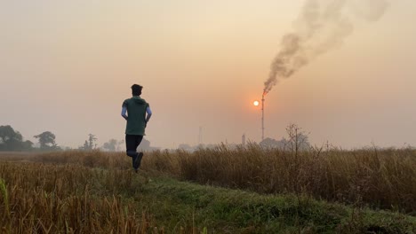 industrial area with smokestack, man jogging on rural countryside path, static