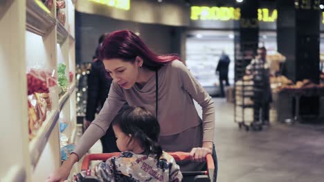 young woman with her toddler son is picking out bread at local grocery store. slomo footage.