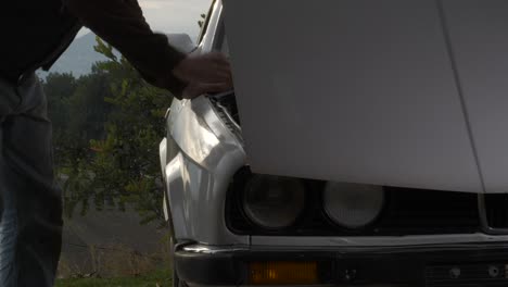 man opening car bonnet inspecting engine bay for maintenance diagnostic servicing outside