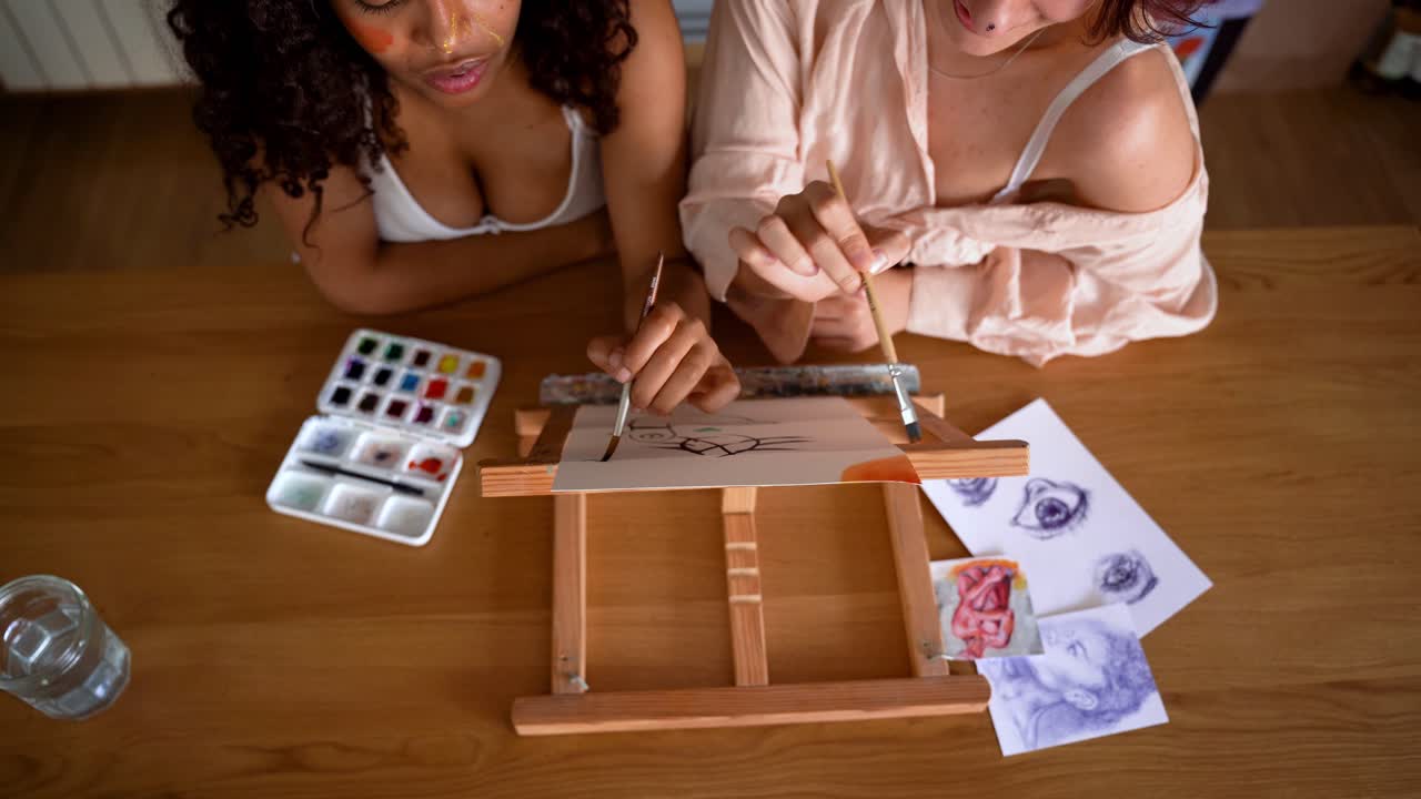 amigas multirraciales concentradas pintando juntas en la mesa