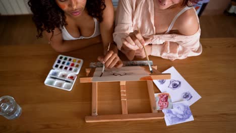 Concentrated-multiracial-girlfriends-painting-together-at-table
