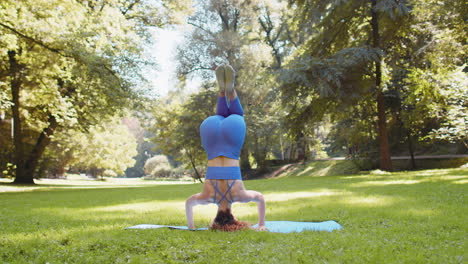 woman performing headstand yoga in a park